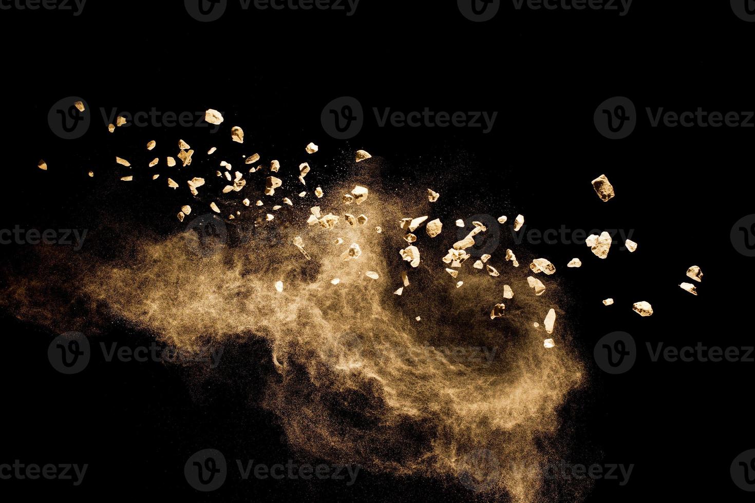 Split debris of  stone exploding with brown powder against black background. photo