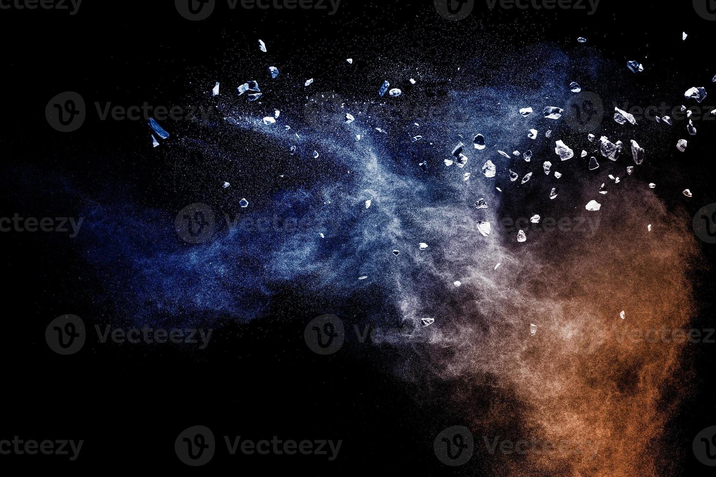 Split debris of  stone exploding with blue powder against black background. photo