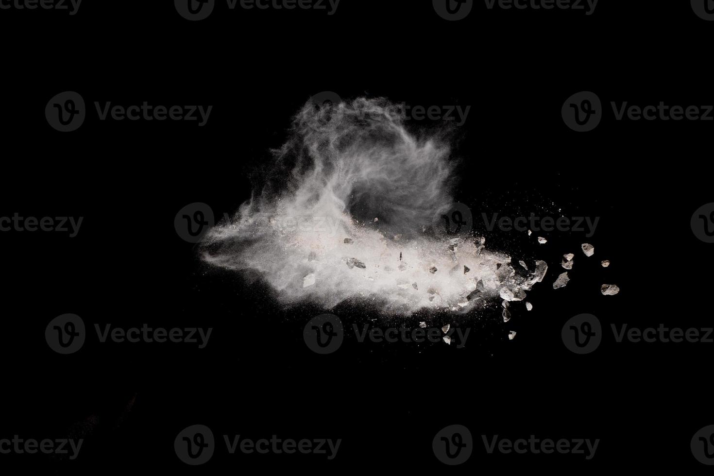 Split debris of stone exploding with white dust against black background. photo