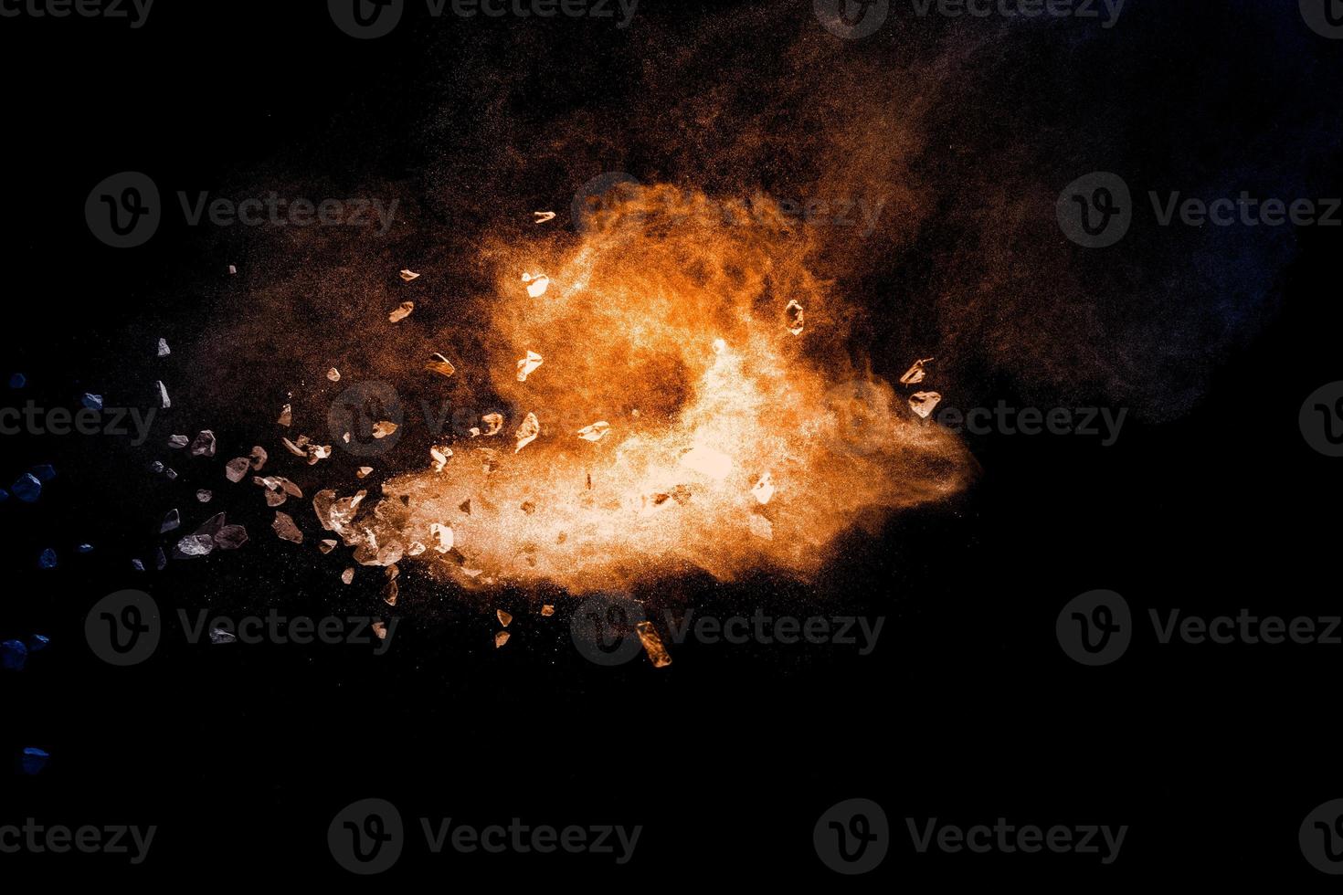 Split debris of stone exploding with orange dust against black background. photo