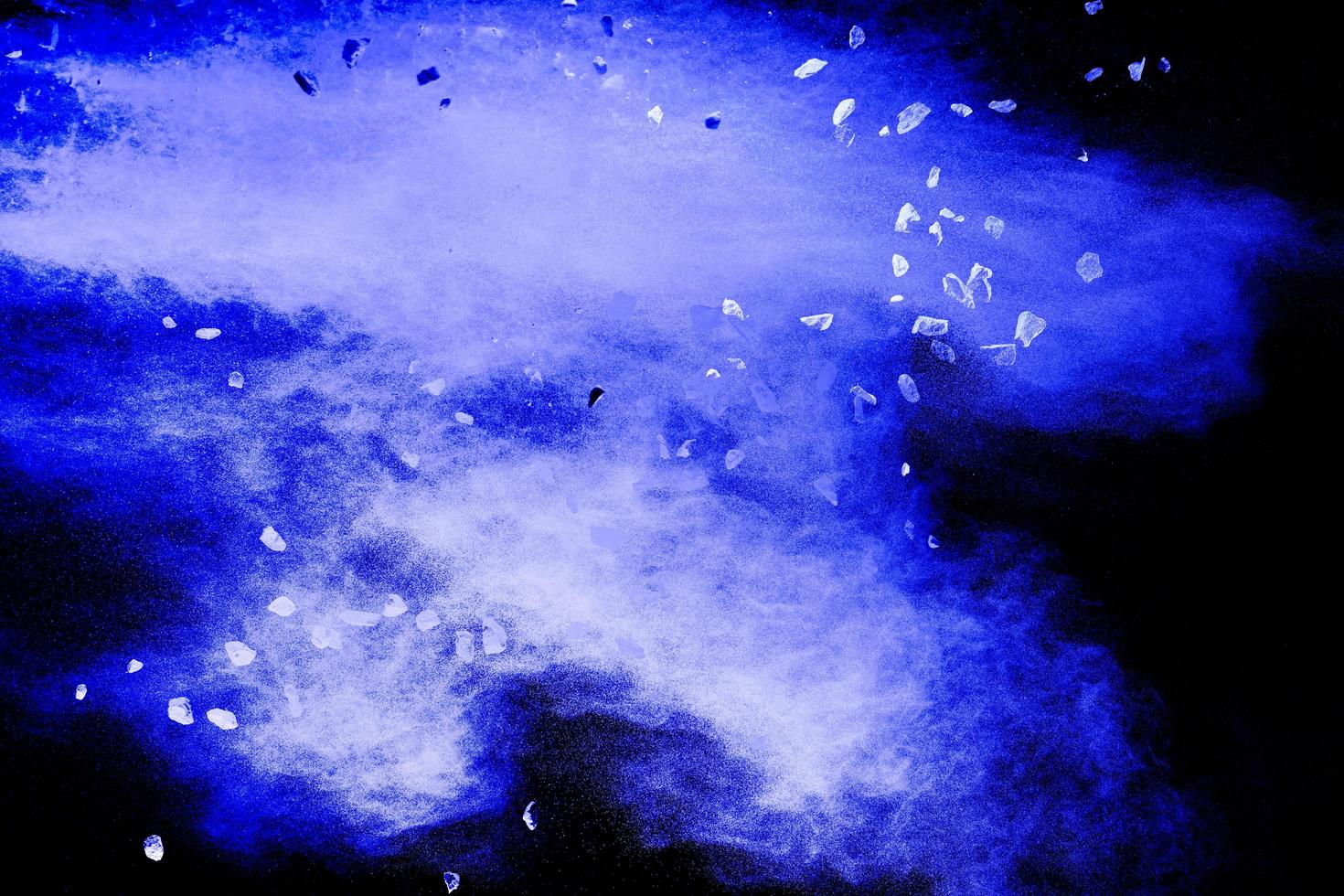 Split debris of stone exploding with blue  powder against black background. photo