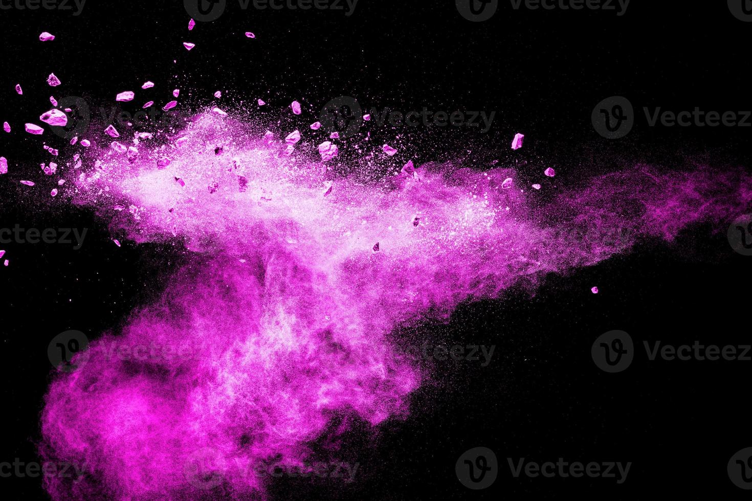 Split debris of stone exploding with pink dust powder against black background. photo