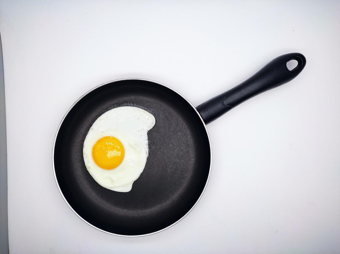 sunny side up eggs on a black pan isolated in white background photo