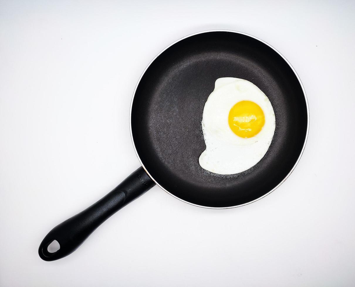 sunny side up eggs on a black pan isolated in white background photo