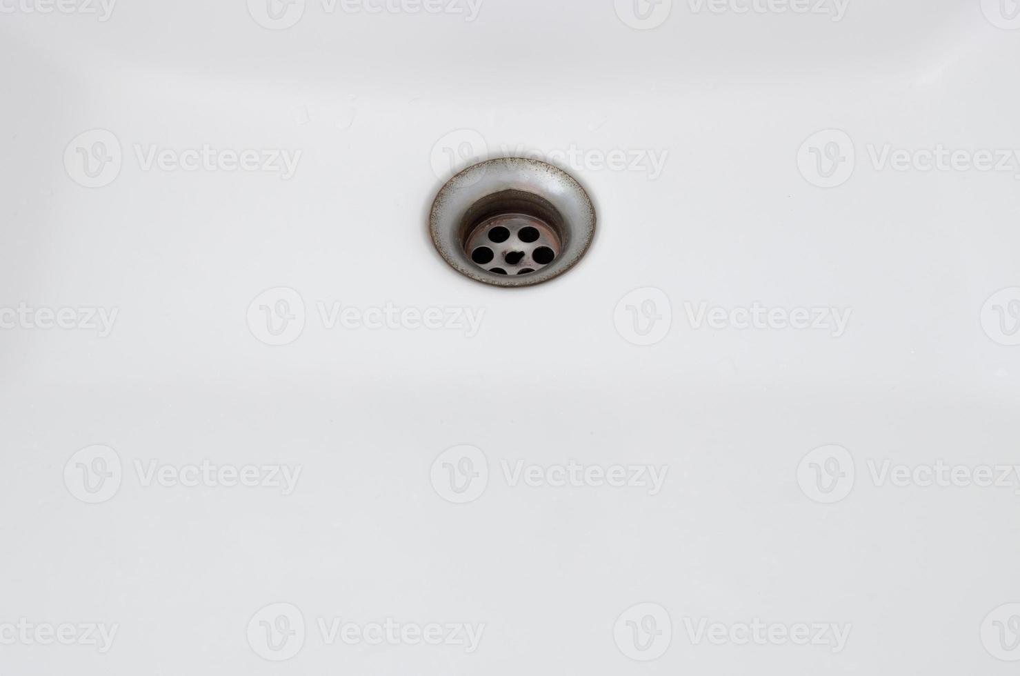 The rusty sinkhole in the white basin of the public toilet. photo