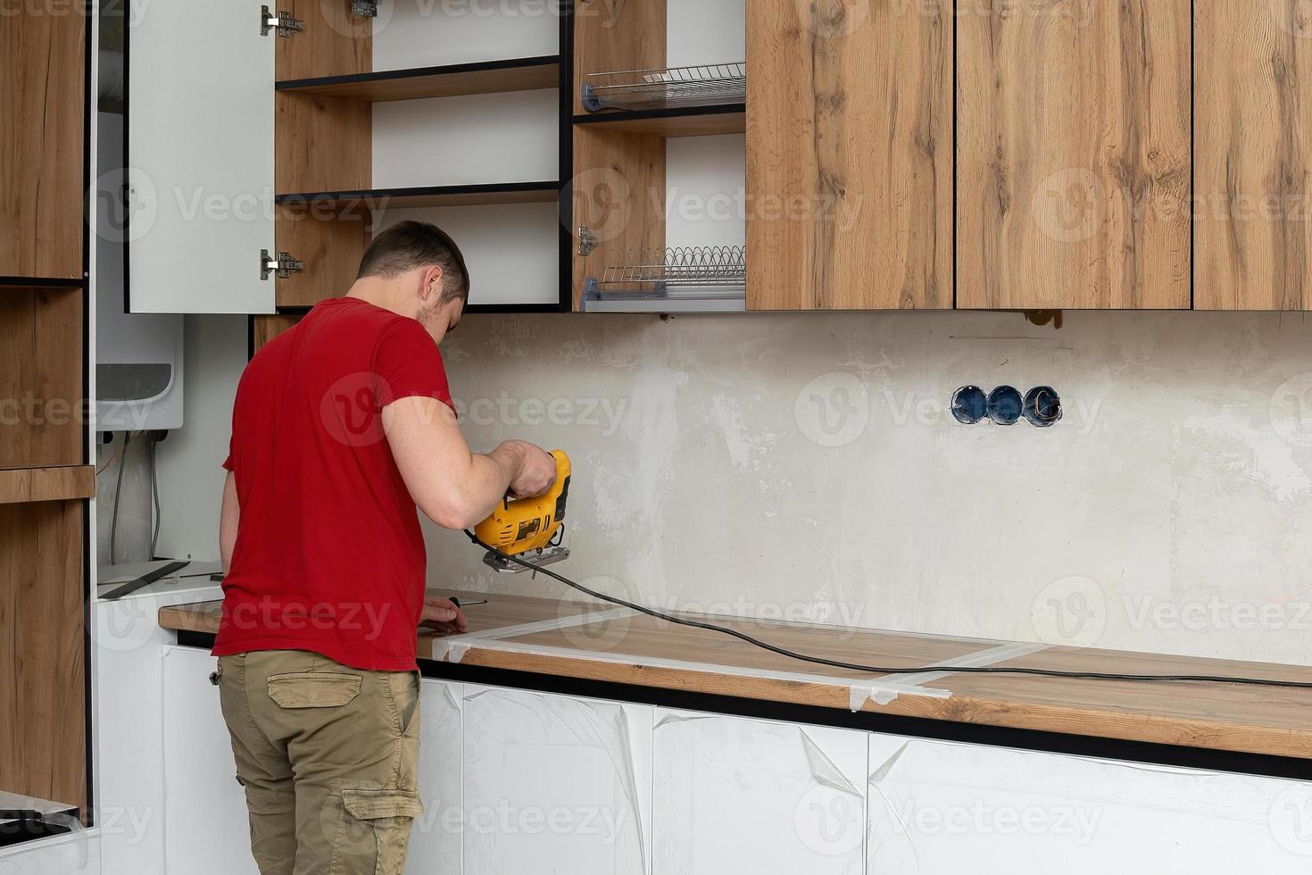 Two craftsmen, furniture makers and assemblers, are installing a modern kitchen in a home, tools in their hands. Concept furniture to order, improvement of living conditions, repair photo