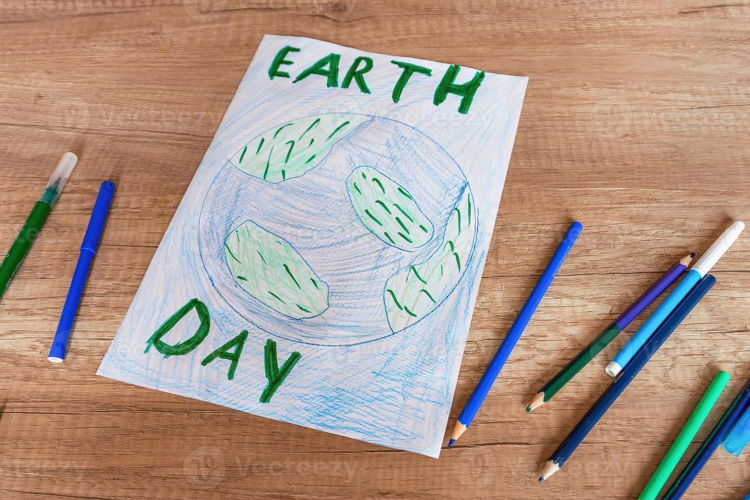 Children's drawing of the planet Earth with a world map with multi-colored pencils and felt-tip pens on white paper. The concept of the day of peace and earth, environmental protection. photo