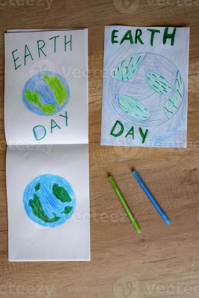 Children's drawing of the planet Earth with a world map with multi-colored pencils and felt-tip pens on white paper. The concept of the day of peace and earth, environmental protection. photo