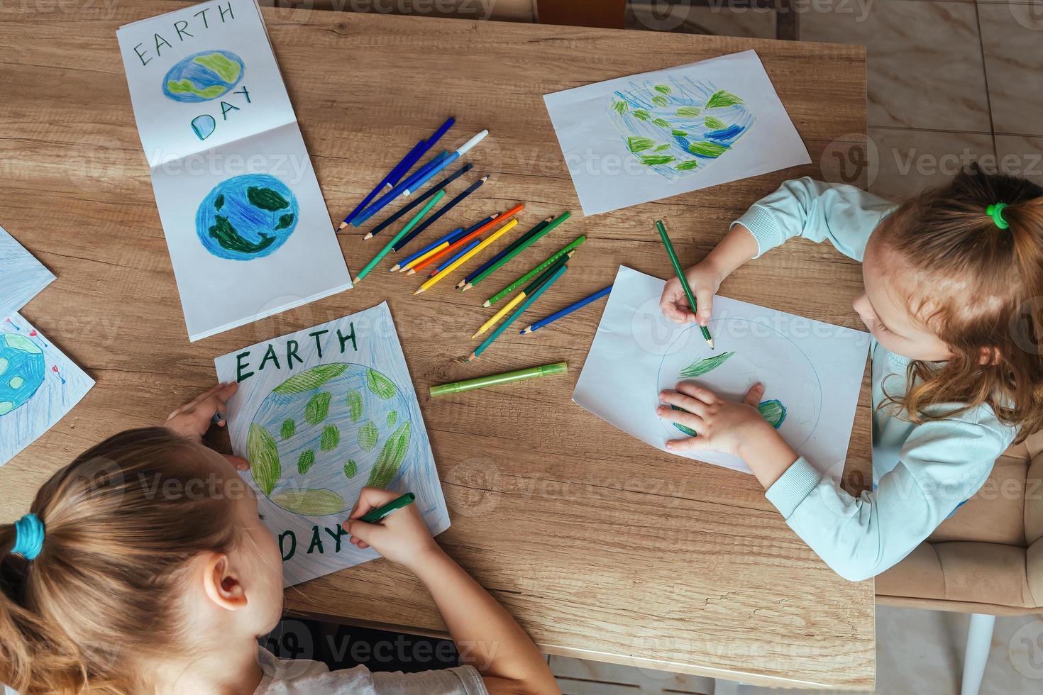 Children draw the planet Earth with pencils and felt-tip pens on album sheets for Earth Day at their home table. The concept of protecting the environment, peace on Earth photo