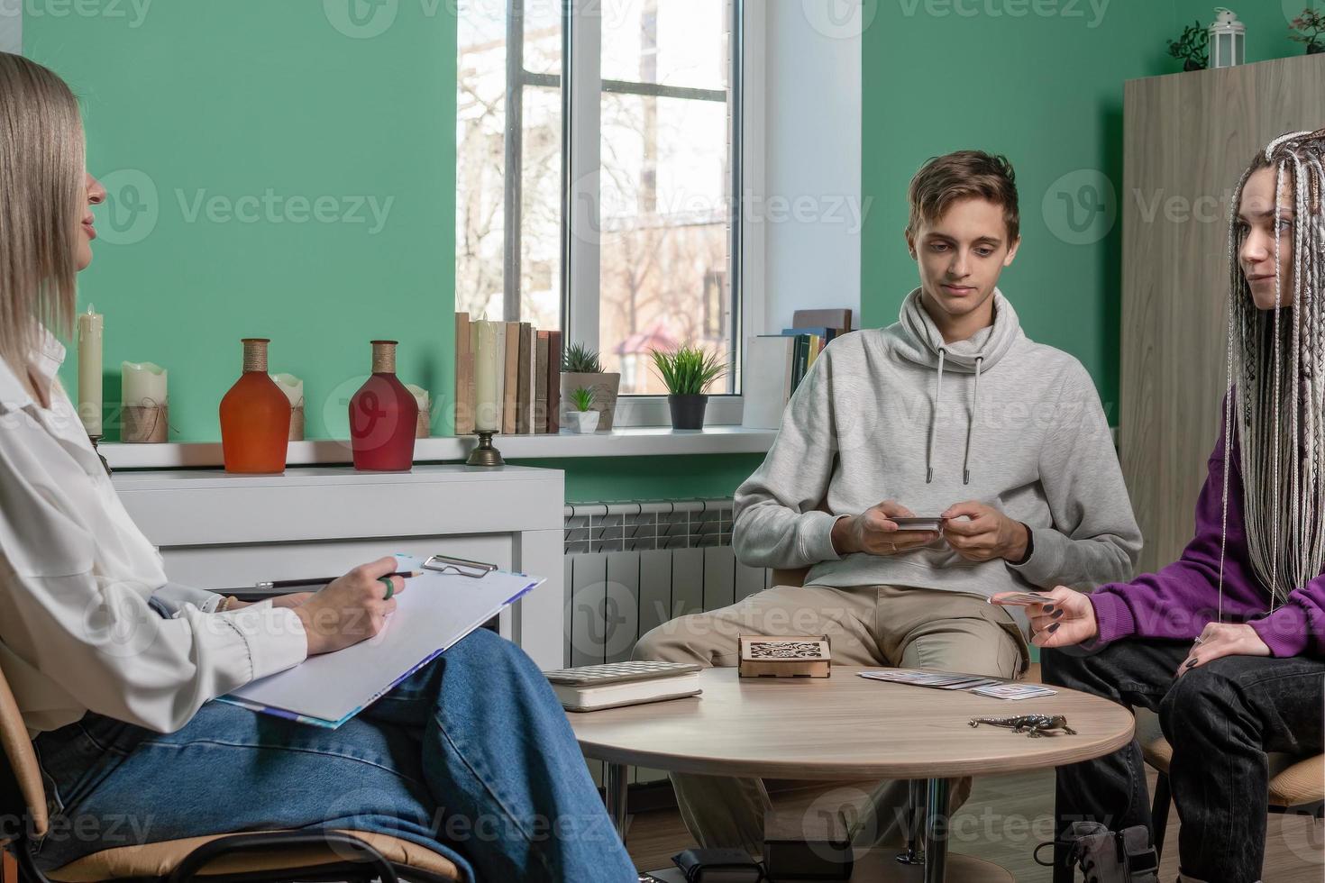 el psicólogo trabajos con clientela, un joven casado Pareja utilizando Mac tarjetas joven personas con psicológico problemas a el recepción de un especialista, psicoterapéutico recepción. foto