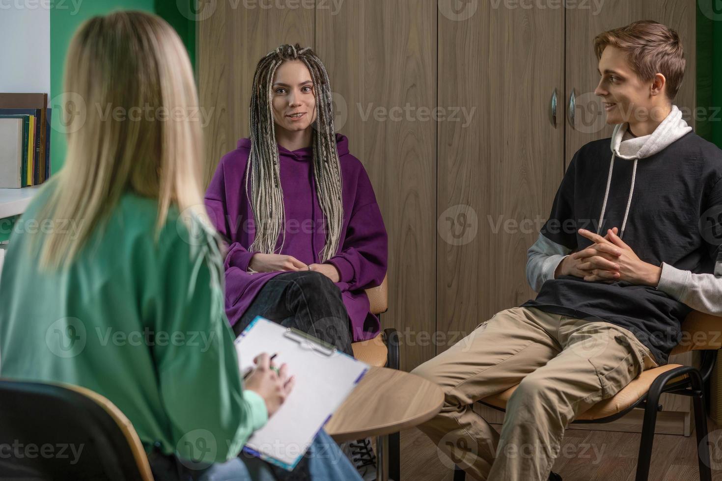 un hembra psicólogo trabajos en su oficina con un joven casado Pareja. en el manos de un especialista son el notas ese ella hace durante el consulta foto