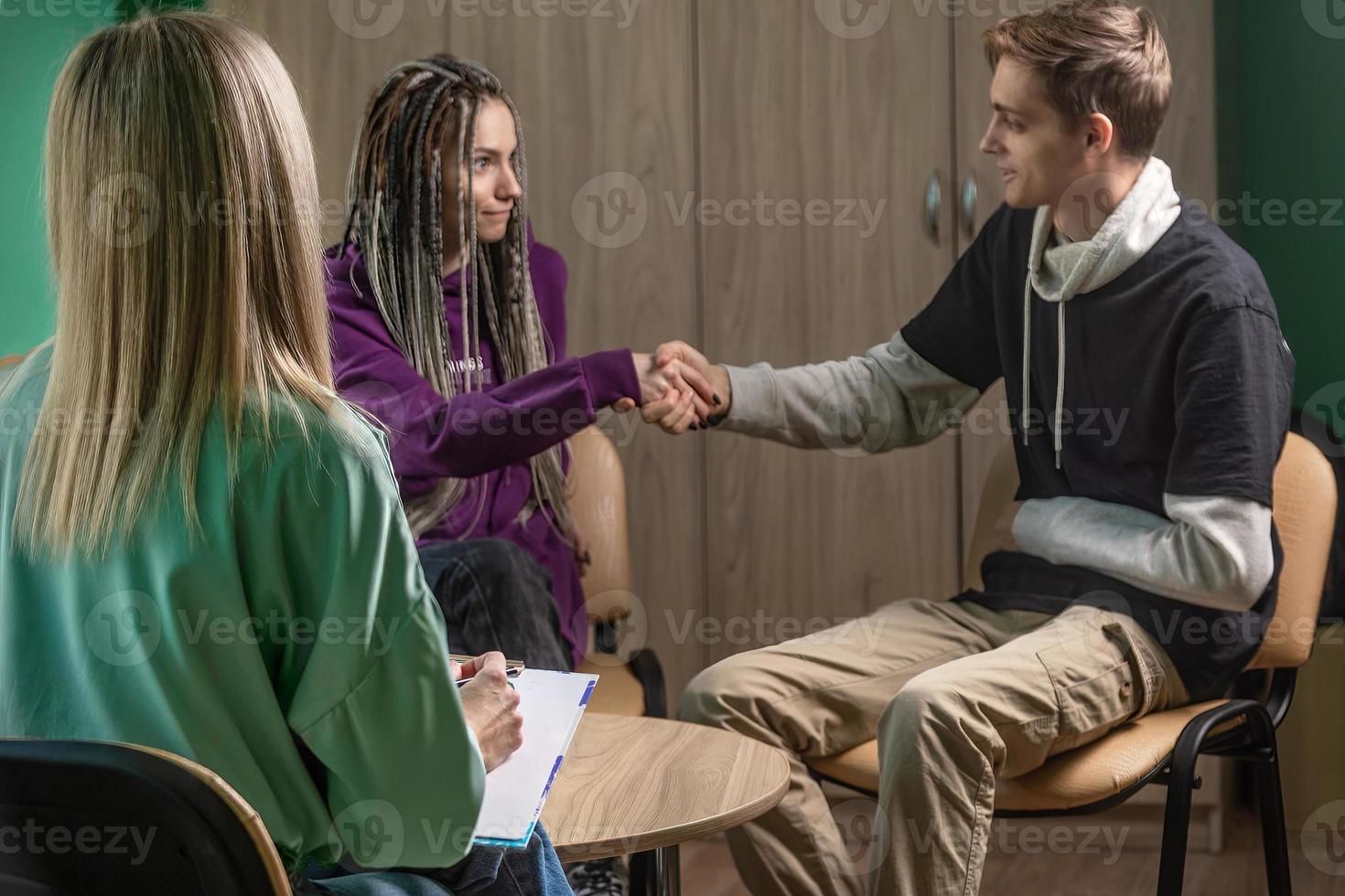 A female psychologist works in her office with a young married couple. In the hands of a specialist are the notes that she makes during the consultation photo