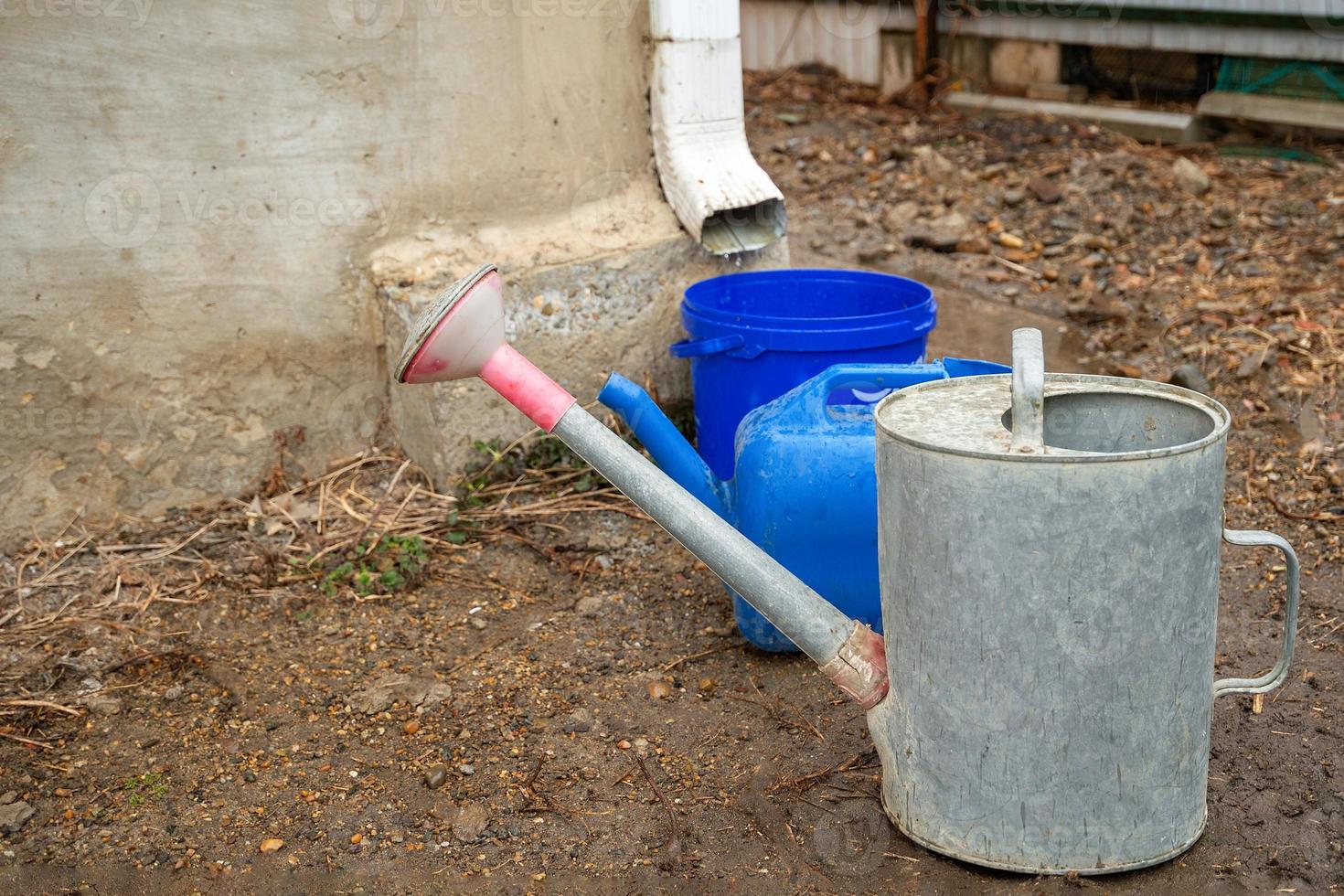 Collection of rainwater in different canisters buckets, watering cans in the yard of his house near the downpipe for further use and watering, space for text photo