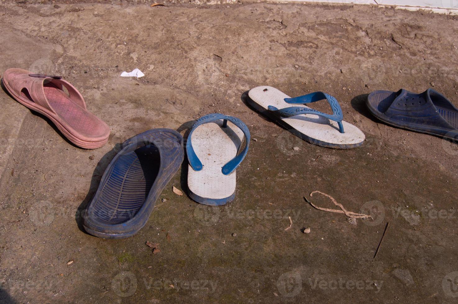 worn sandals scattered on the ground photo