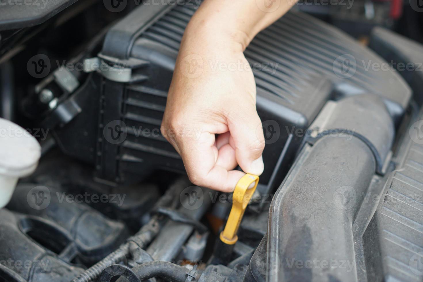 Closeup hand hold yellow scale for fuel measurement level in car engine. Concept, automobile maintenance. Check and repair before driving for safety. Basic diagnose vehicle problems. photo