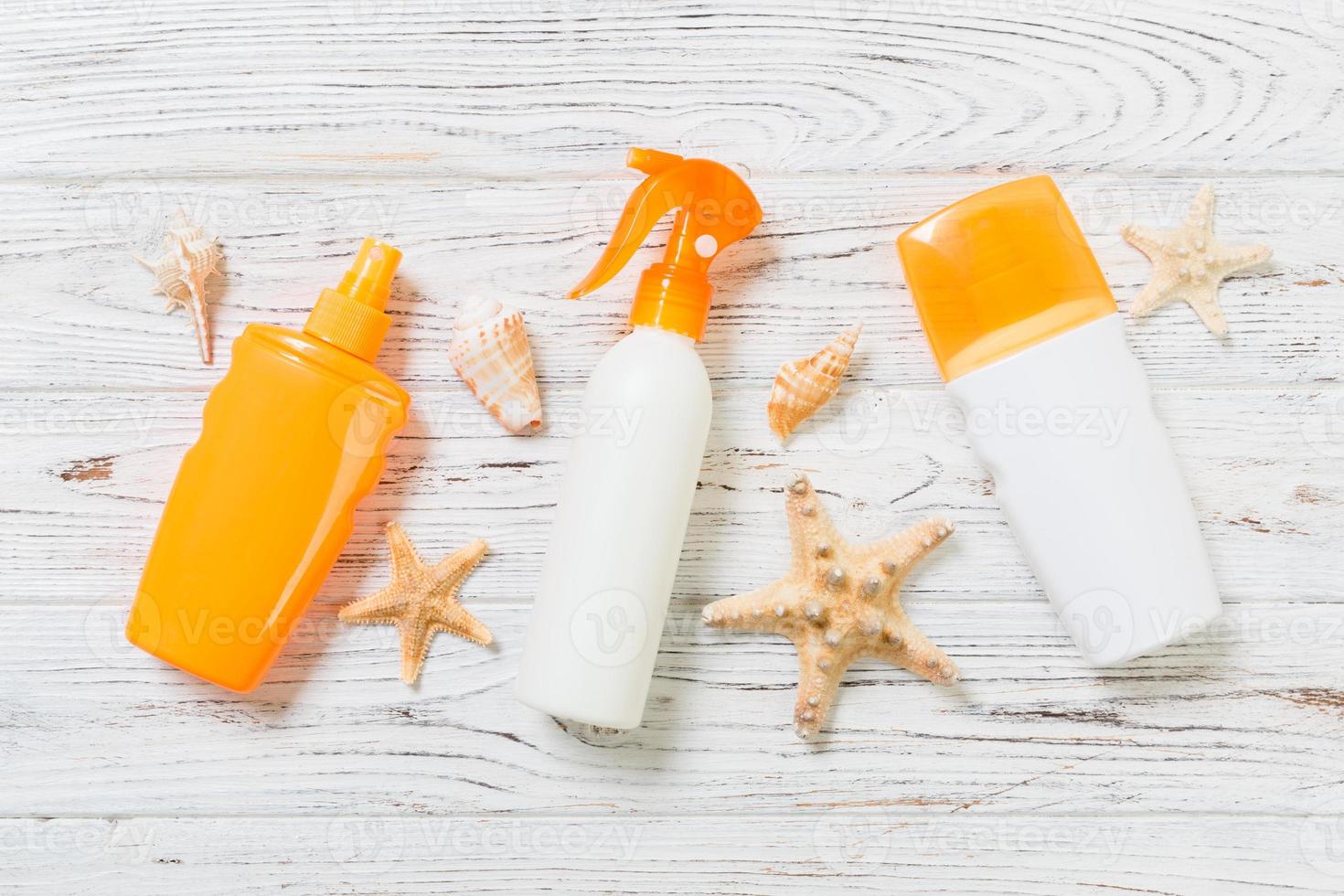 flat lay concept summer travel vacation. Sunscreen bottles with starfish on white wooden table with copy space photo