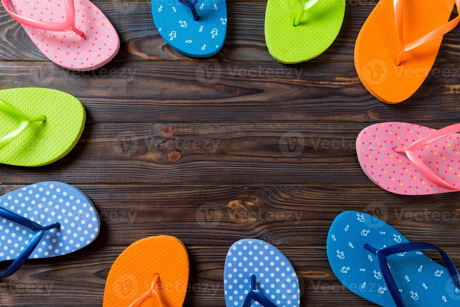 a lot of flip flop colored sandals, summer vacation on wooden background, copy space top view photo