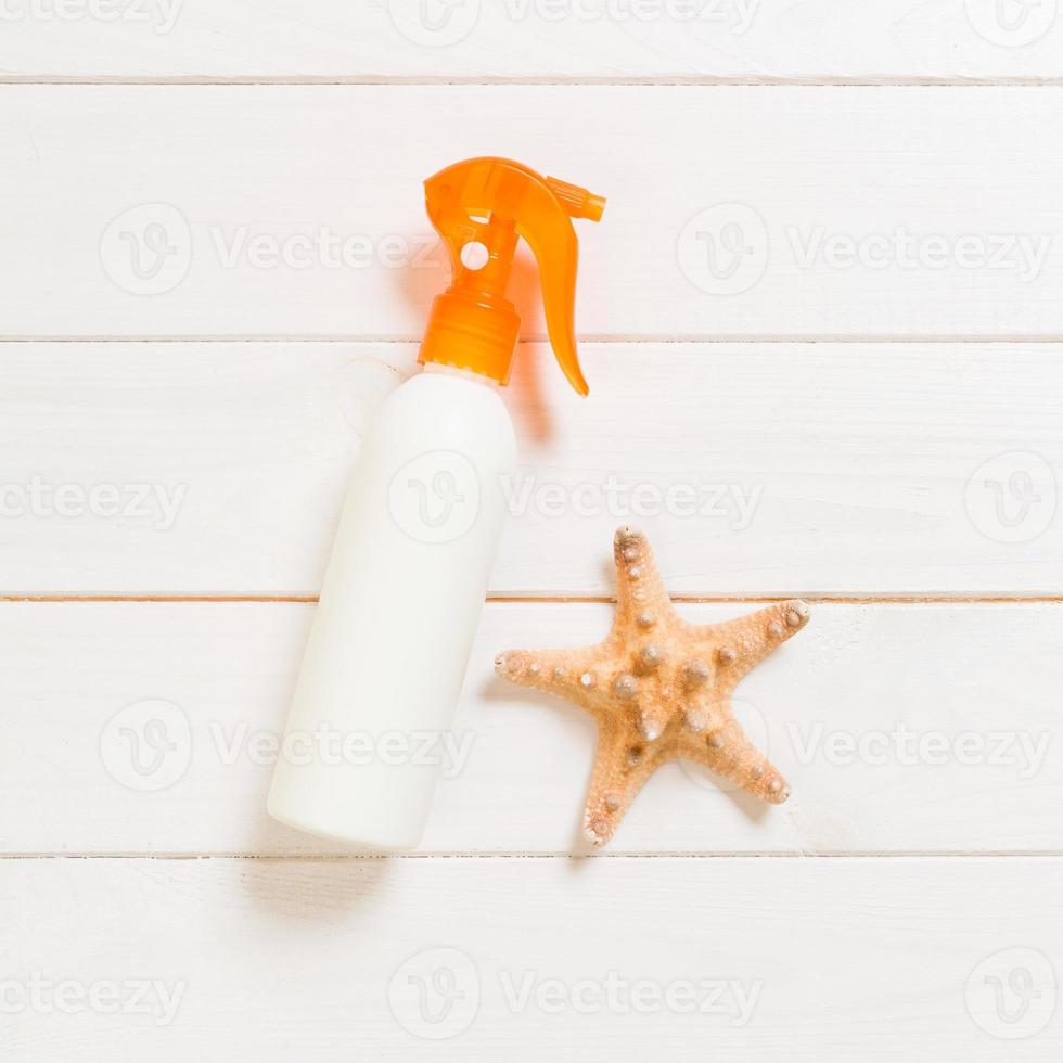 flat lay concept summer travel vacation. Sunscreen bottles with starfish on white wooden table with copy space photo