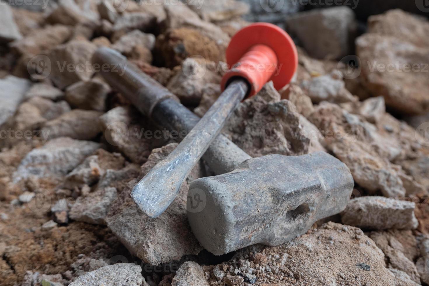 selective focus to stone chisel and hammer on collapsed building rubble, demolished building renovation and evacuation concept, soft focus photo