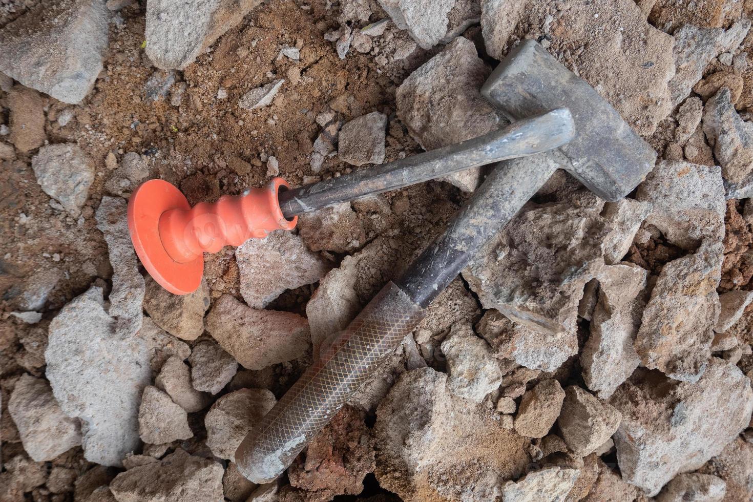 selective focus to stone chisel and hammer on collapsed building rubble, demolished building renovation and evacuation concept, soft focus photo