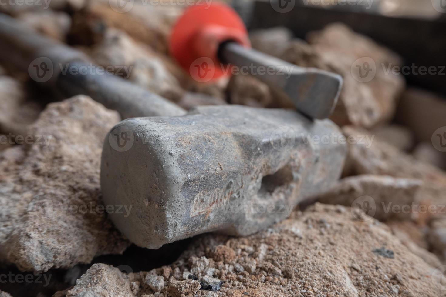 selective focus to stone chisel and hammer on collapsed building rubble, demolished building renovation and evacuation concept, soft focus photo