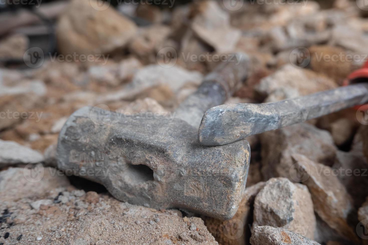 selective focus to stone chisel and hammer on collapsed building rubble, demolished building renovation and evacuation concept, soft focus photo