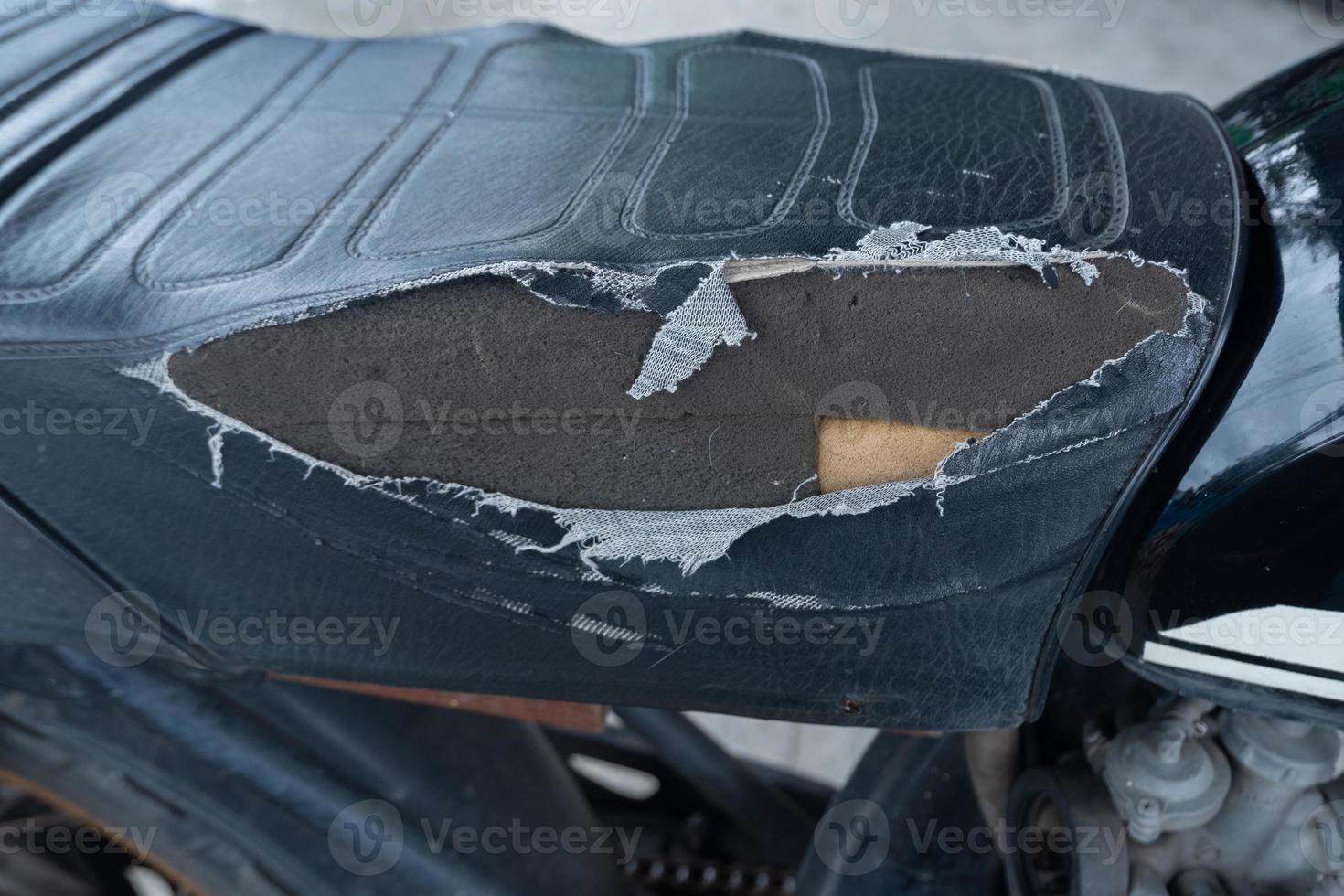 selectivo fokus en el lacerado motocicleta asiento , antiguo negro cuero asiento es dañar , roto cuero. foto