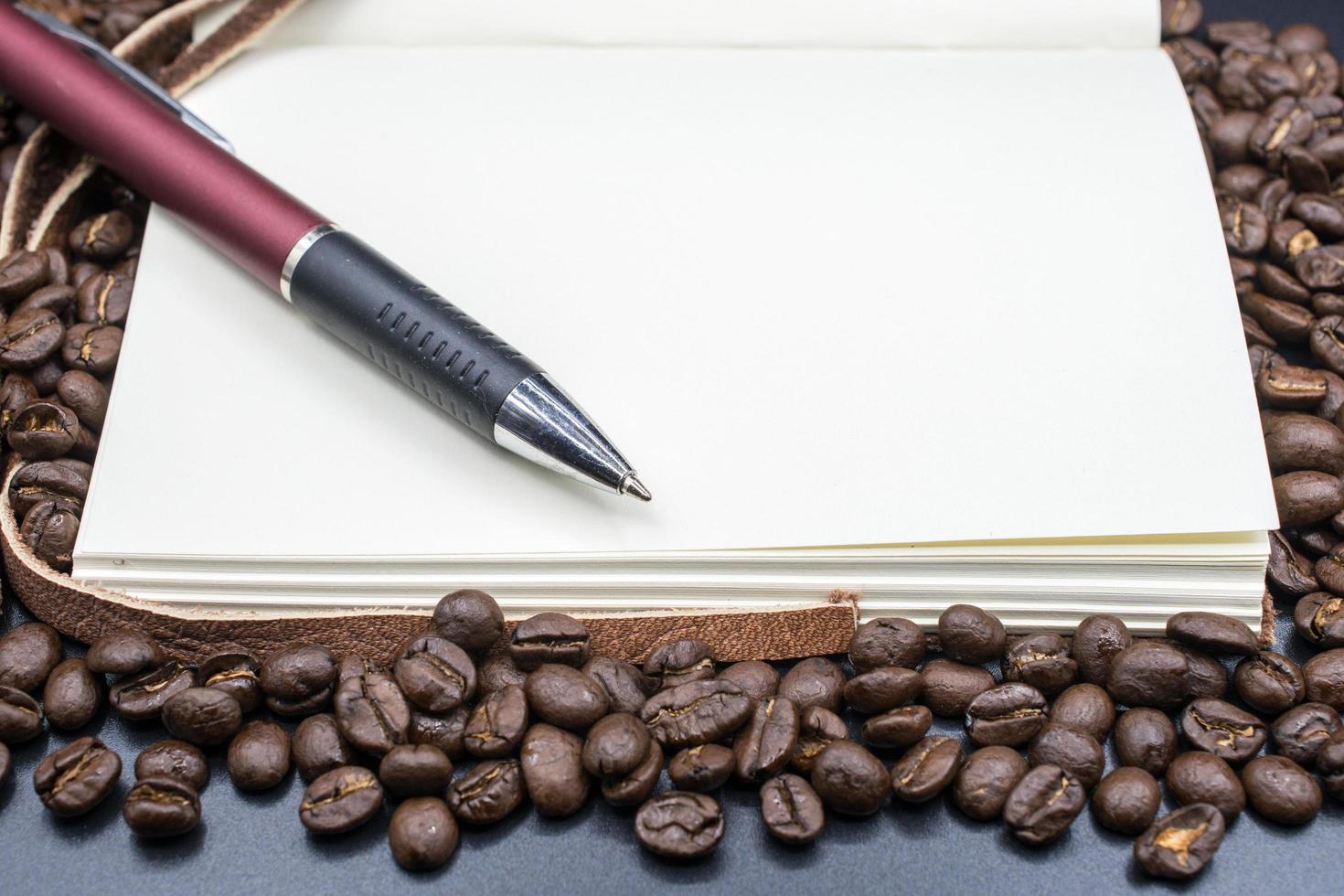 A book open the empty page on the roasted coffee beans with isolated black background. photo