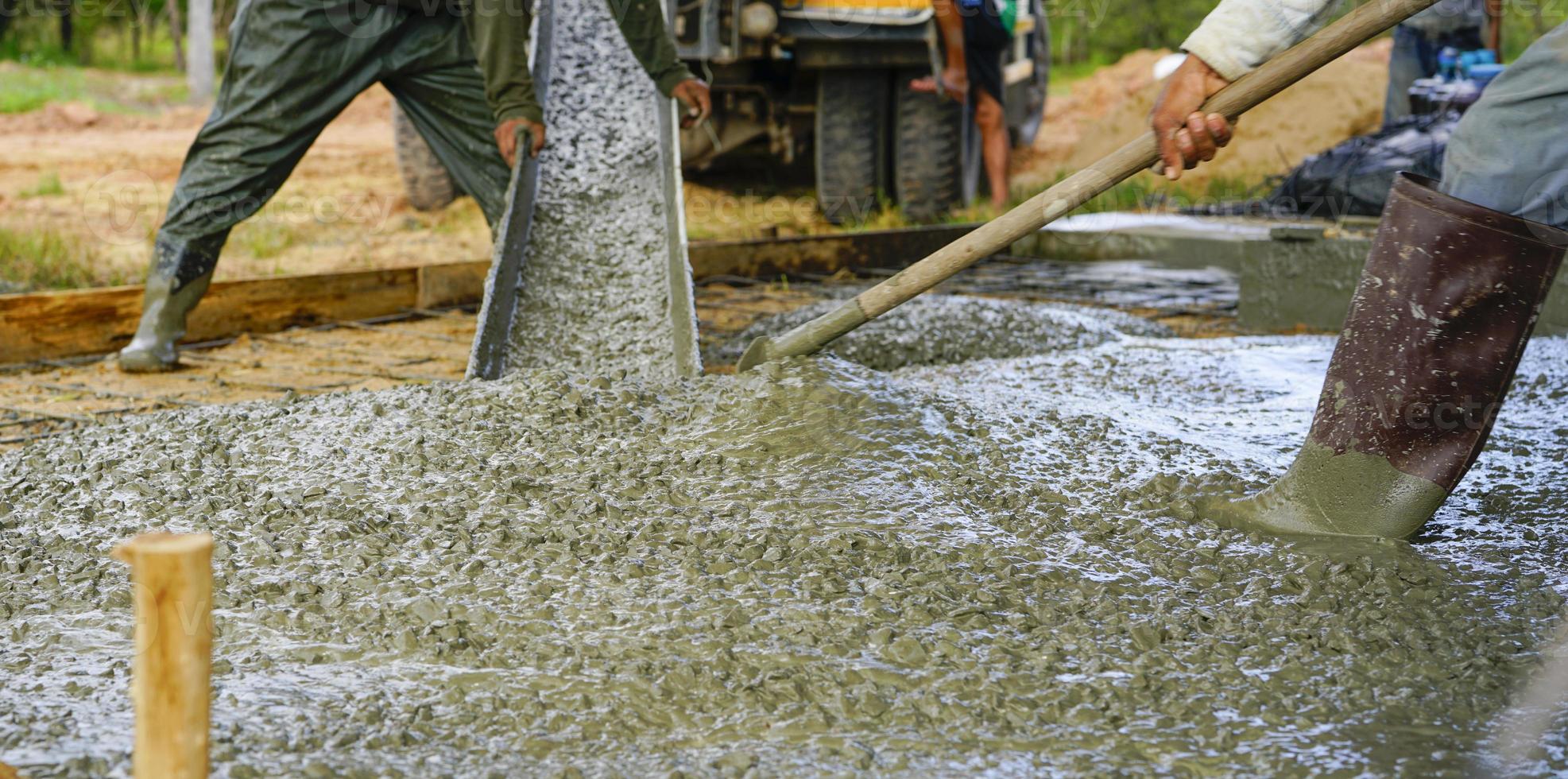 Construction worker pour wet concrete at construction site. Construction worker working with ready-mix concrete pouring from cement mixer truck. Construction concractor concept. Builder pour cement. photo