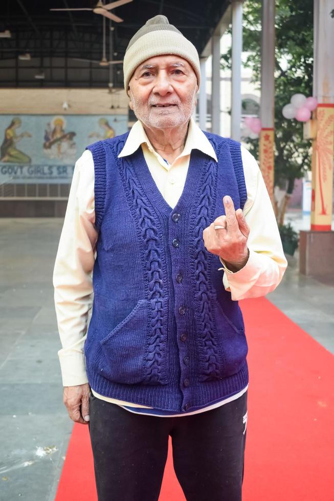 New Delhi, India - December 04 2022 - Unidentified people showing their ink-marked fingers after casting votes in front of polling booth of east Delhi area for MCD local body Elections 2022 photo