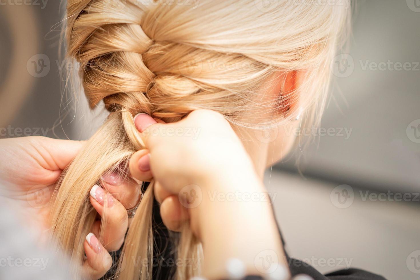 Female hands braiding pigtail to woman photo