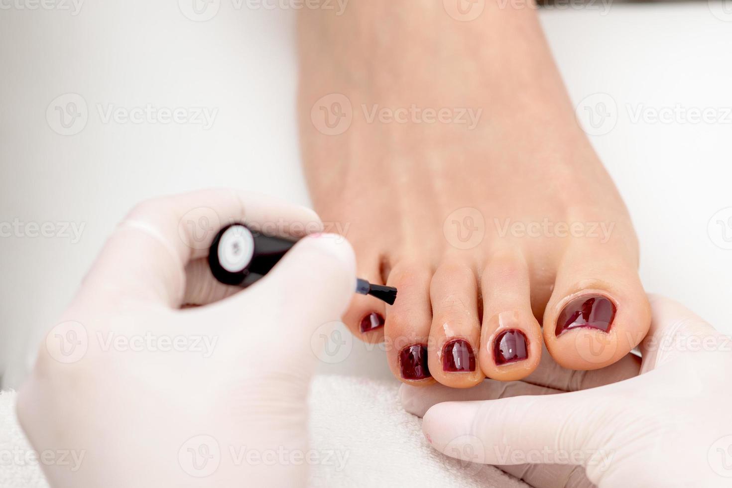 Manicure master is painting female toenails photo
