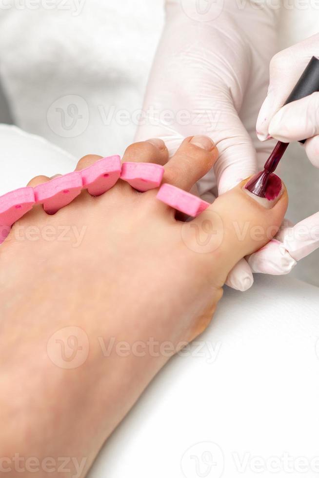 Manicure master is painting female toenails photo