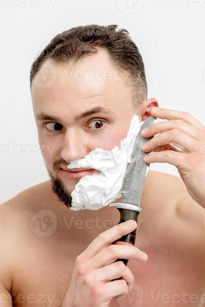 hombre afeitándose la barba con un cuchillo foto