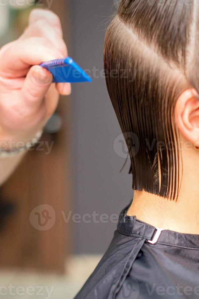 Hairdresser doing haircut of young woman photo