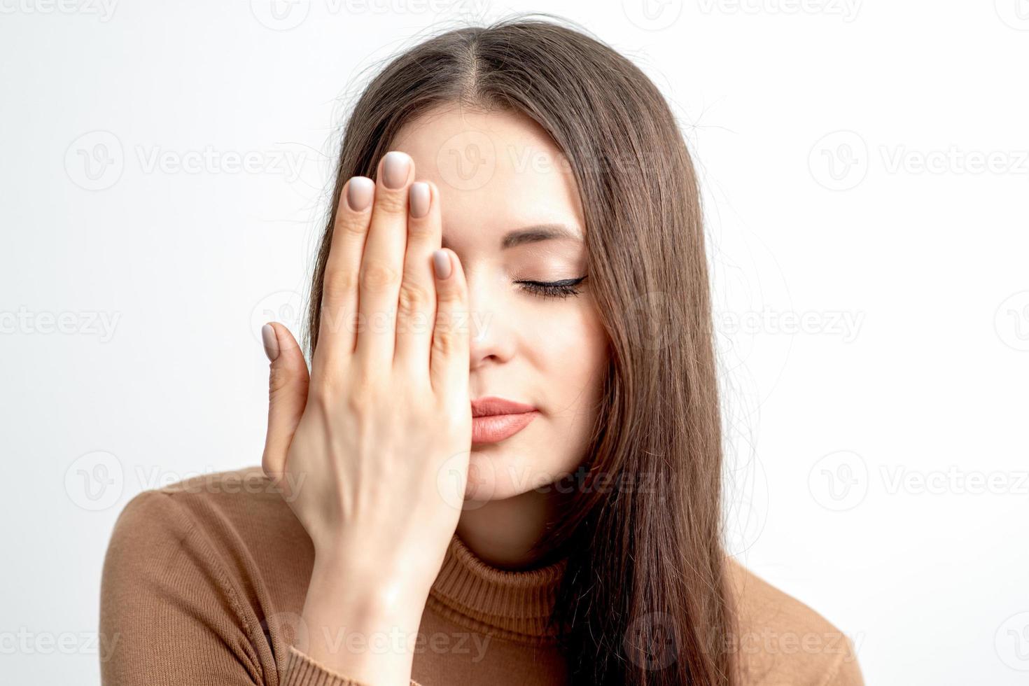Woman with closed eyes covering one eye photo