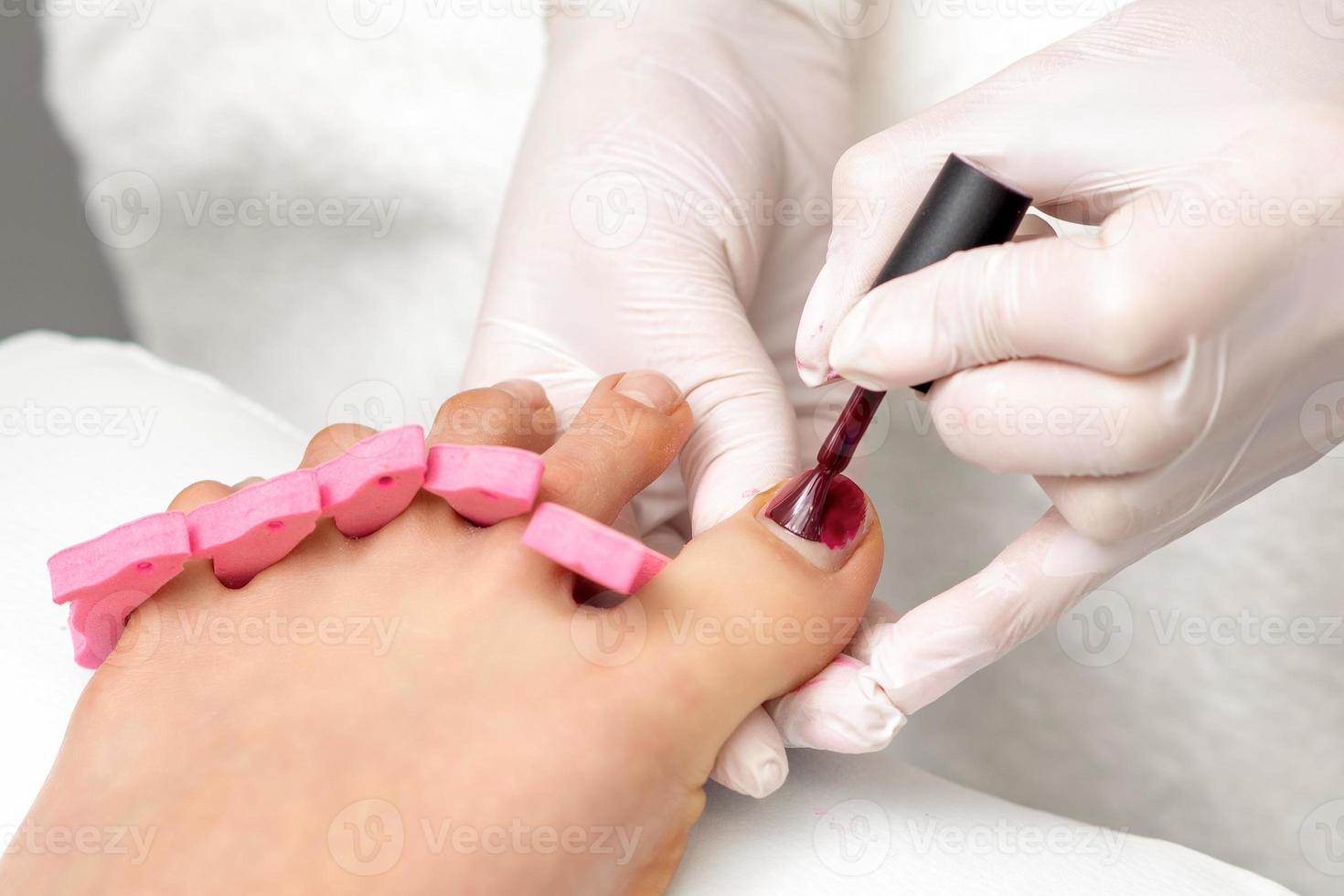 Manicure master is painting female toenails photo