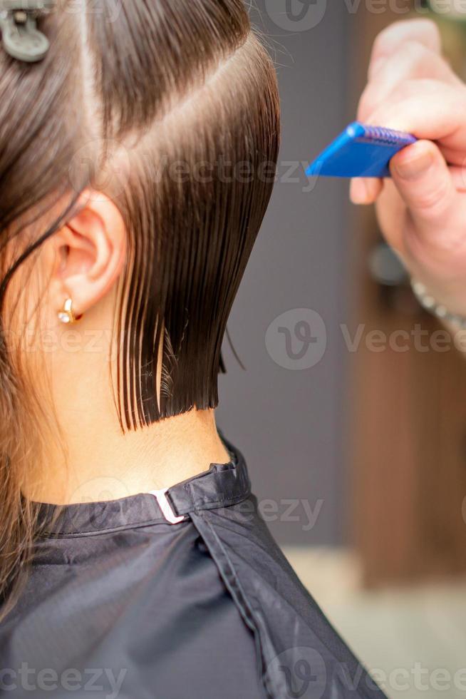 peluquero haciendo Corte de pelo de joven mujer foto