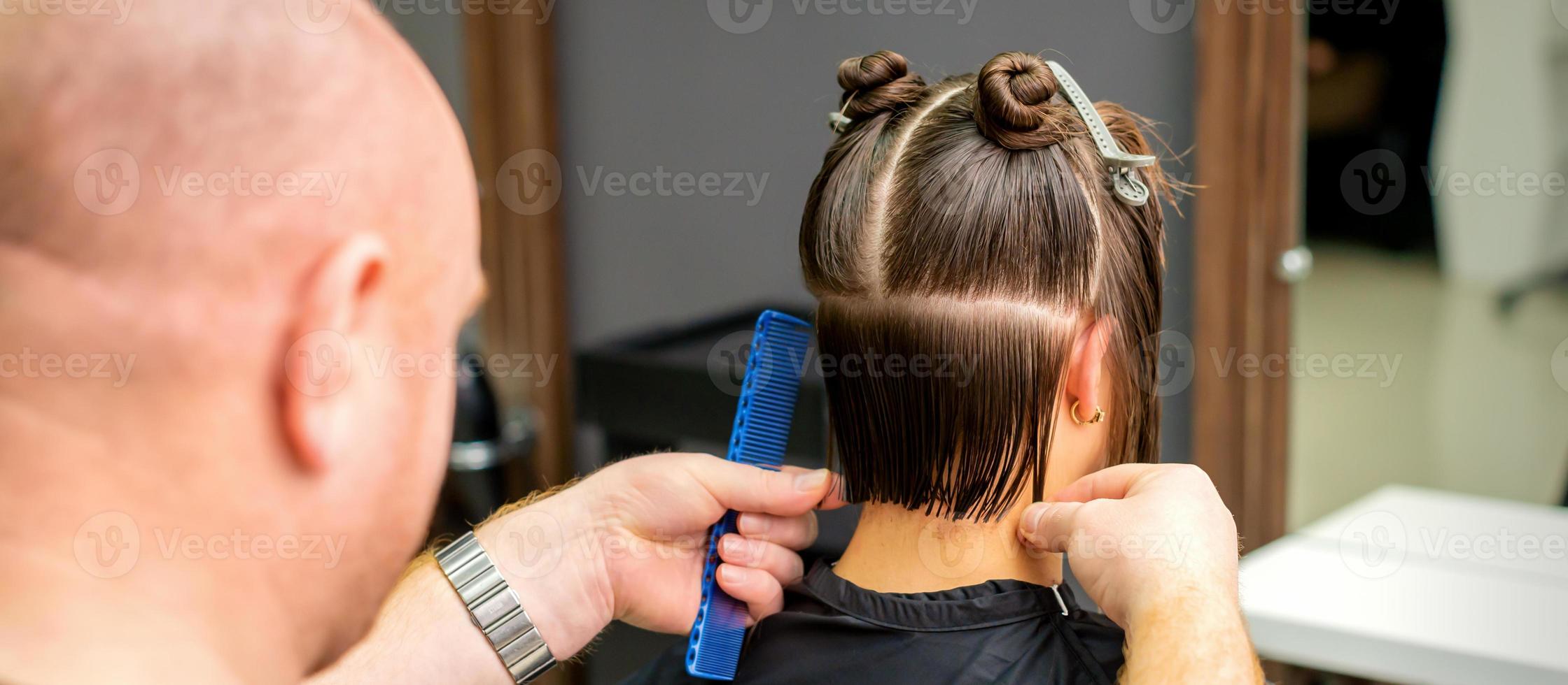 Male hairdresser cutting hair of woman photo