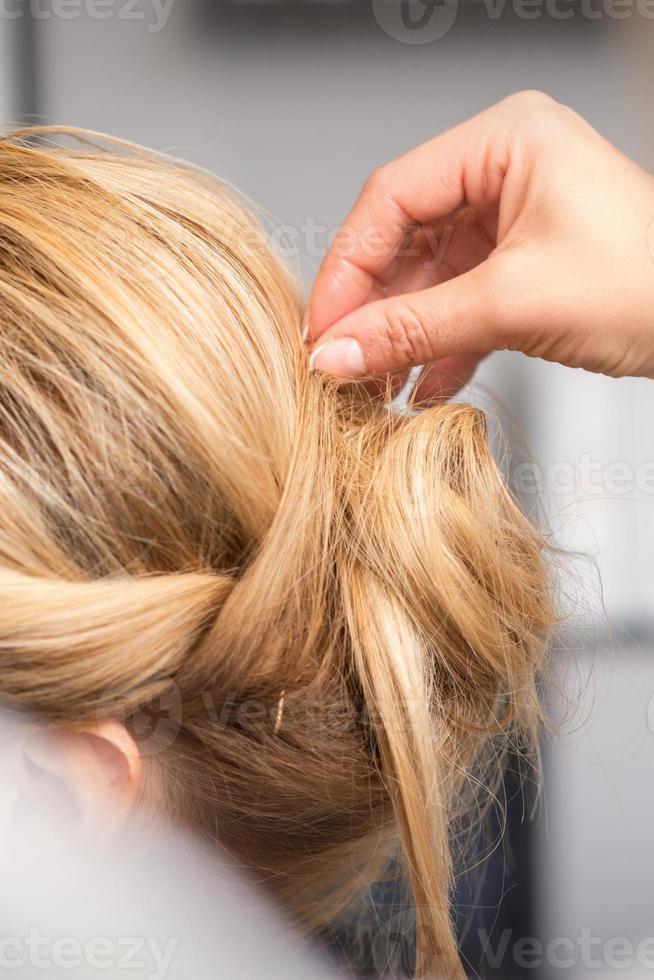 hairdresser makes hairstyle of young woman photo