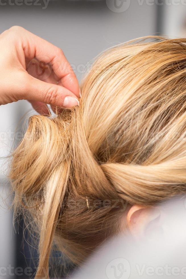 hairdresser makes hairstyle of young woman photo