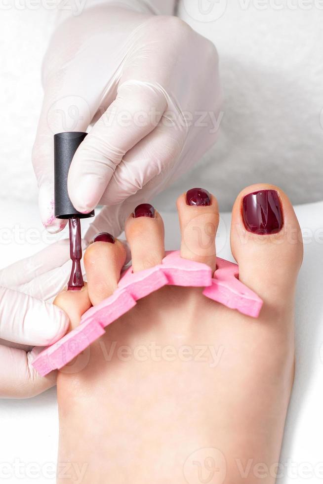 Manicure master is painting female toenails photo