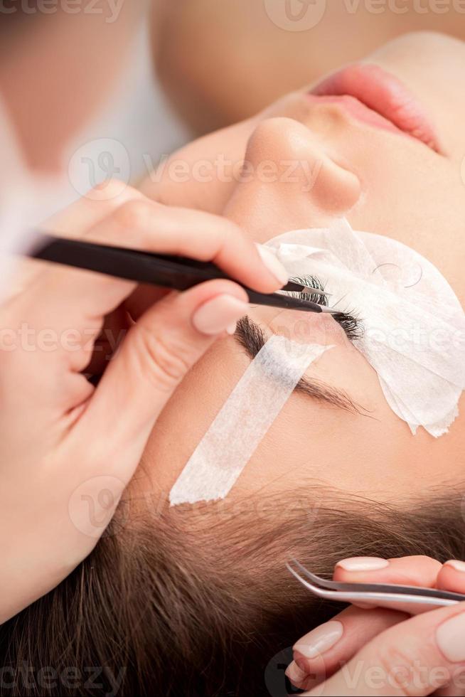 Woman receiving eyelash extensions procedure photo