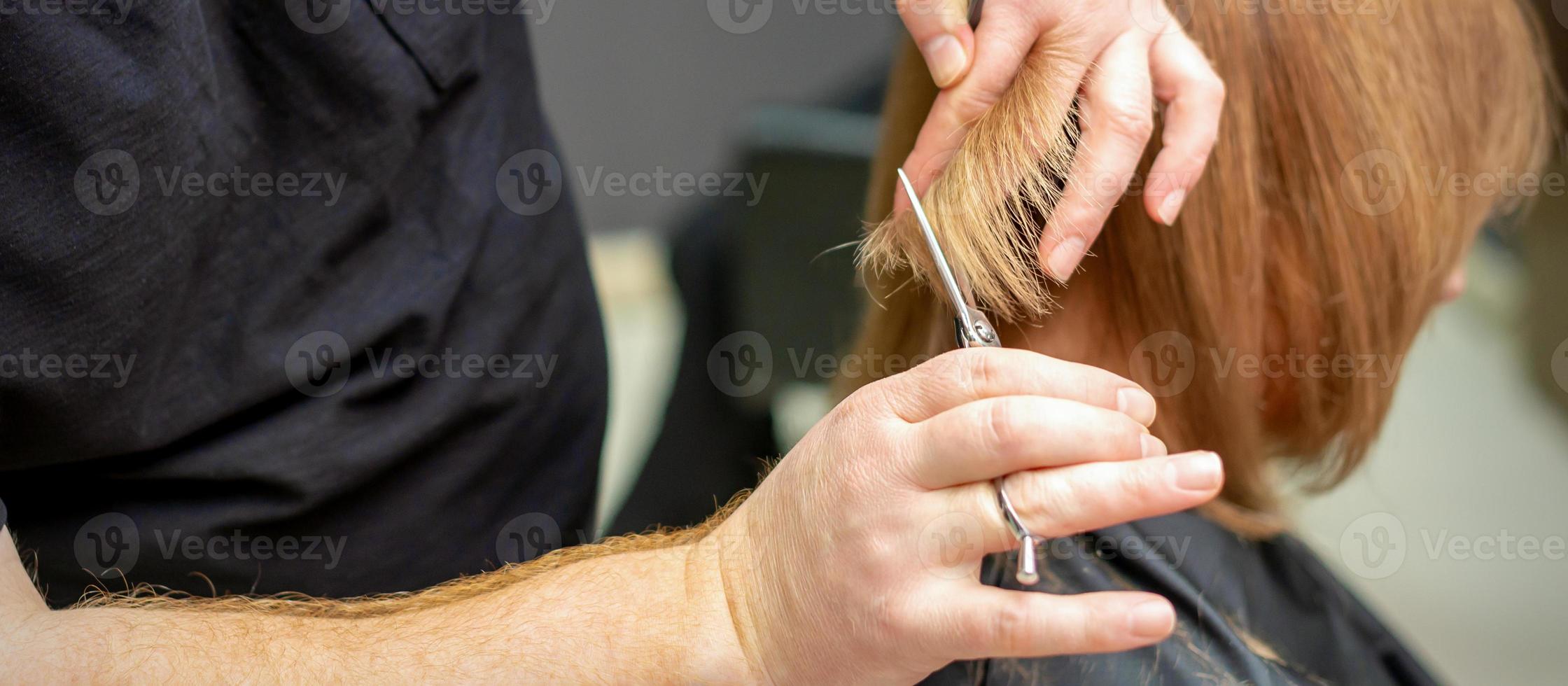 Hairdresser cuts hair to young woman photo