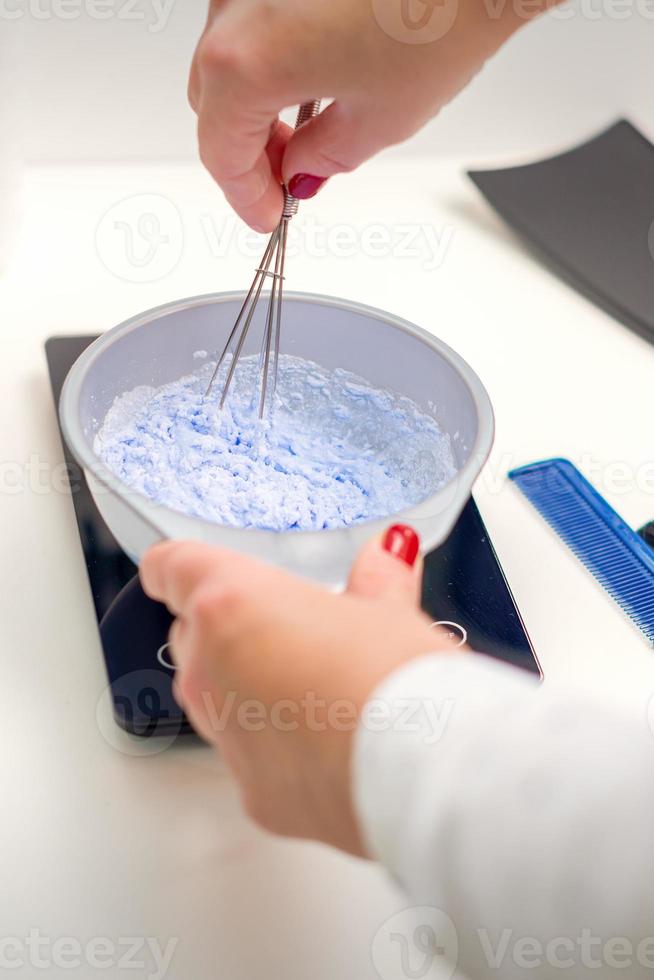 Hairdresser is mixing dye in white bowl photo