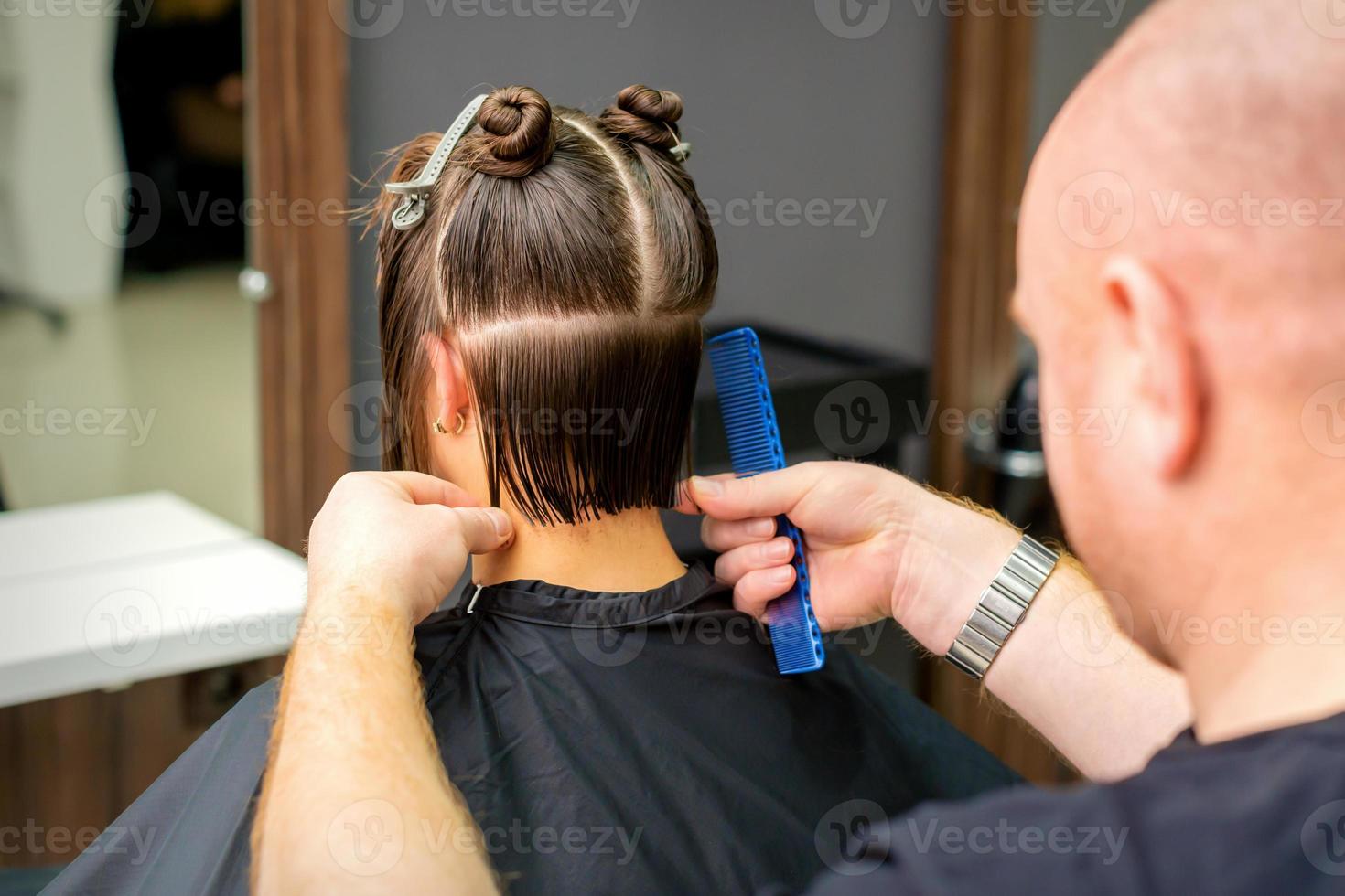 Male hairdresser cutting hair of woman photo