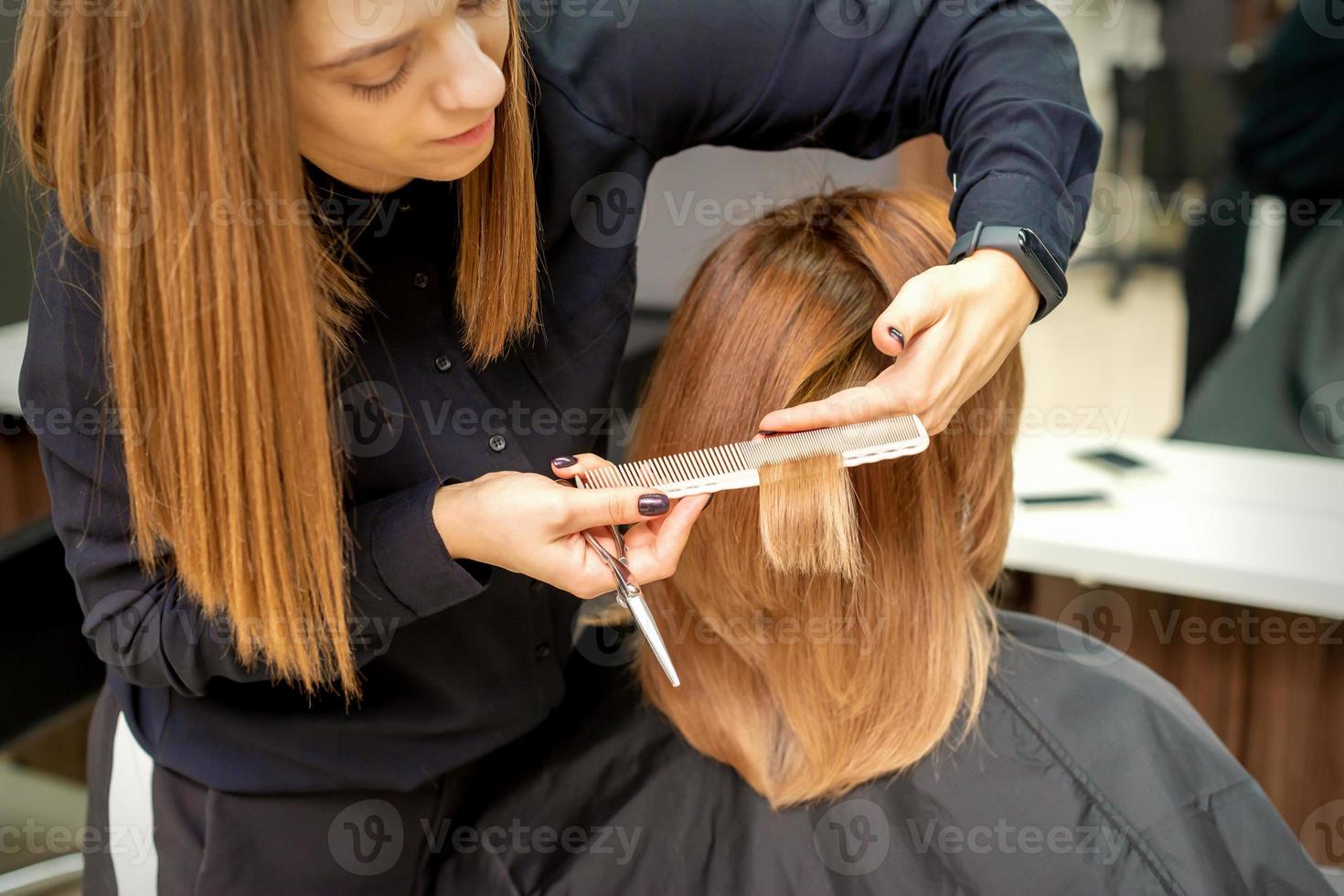 Hairdresser cuts hair to young woman photo