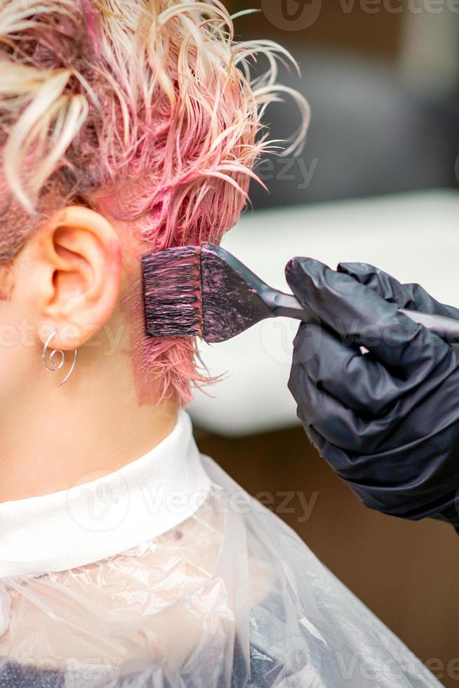 Hairdresser dyeing hair in pink color photo