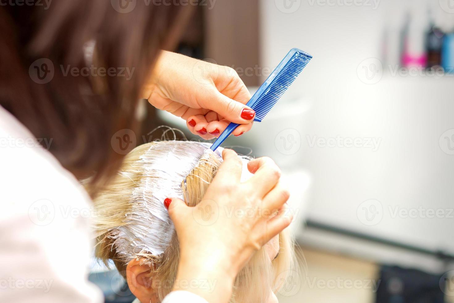 Professional hairdresser dyeing hair in white photo