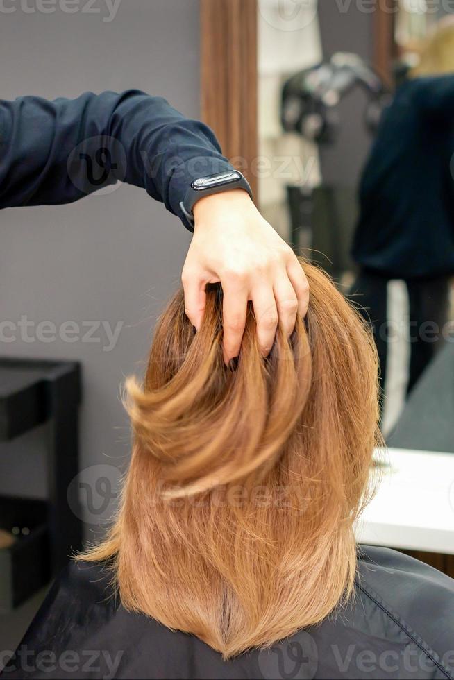 Hairdresser checks hairstyle of woman photo